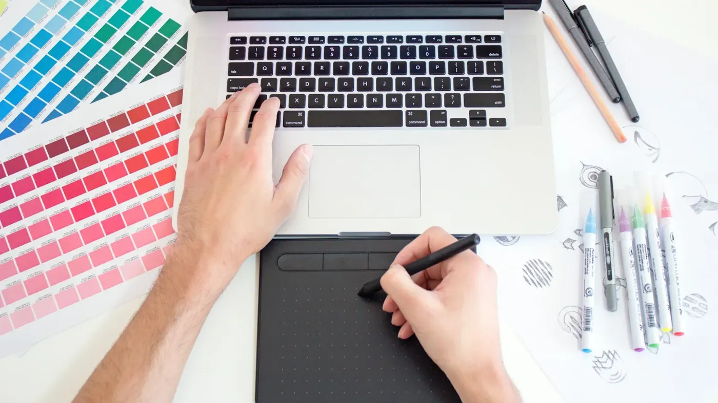 A designer working with a drawing tablet and laptop