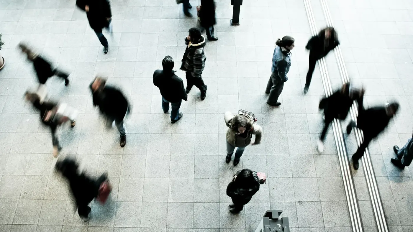 Commuters crossing a railway station concourse, seen from above