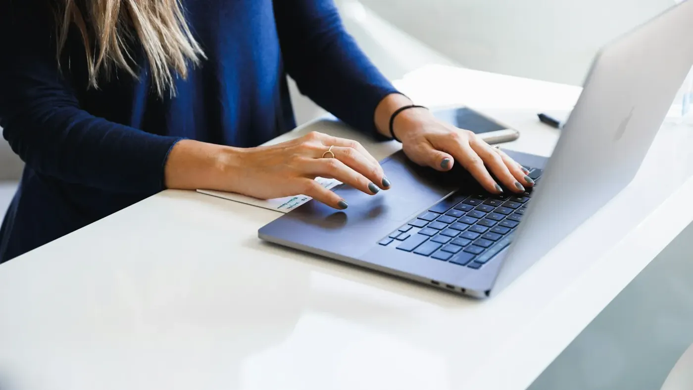 A woman working on a laptop at a desk